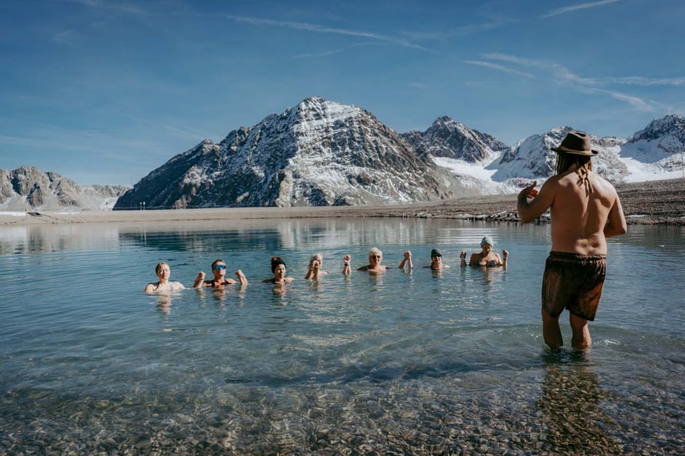 Begleitetes Eisbad im Bergsee vor schneebedeckten Gipfeln
