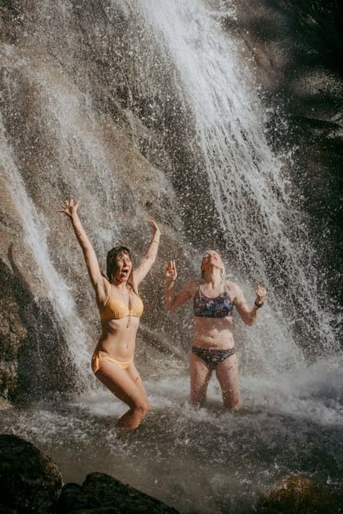 Zwei Teilnehmerinnen stehen lachend unter einem Wasserfall