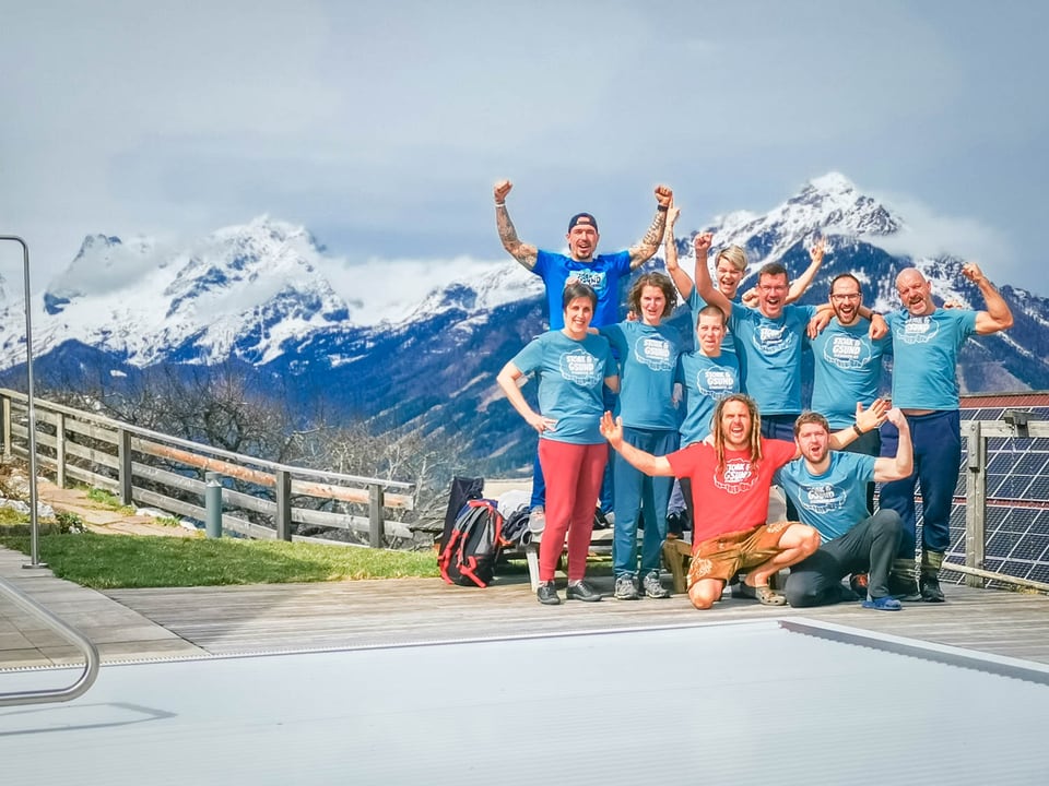 Retreatgruppe jubelt vor dem Bergpanorama am Pool des Luxus-Bergchalets